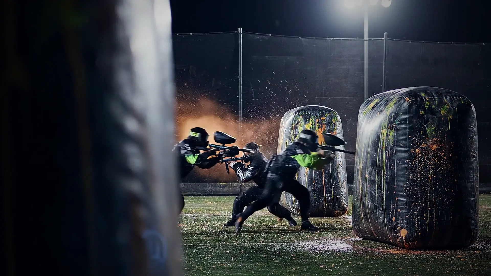 Speedball players sprinting off the break at a night tournament, paint flying
